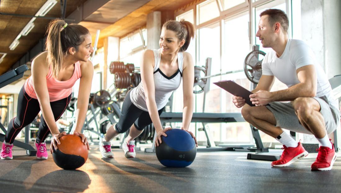 Fitness trainer working with two customers